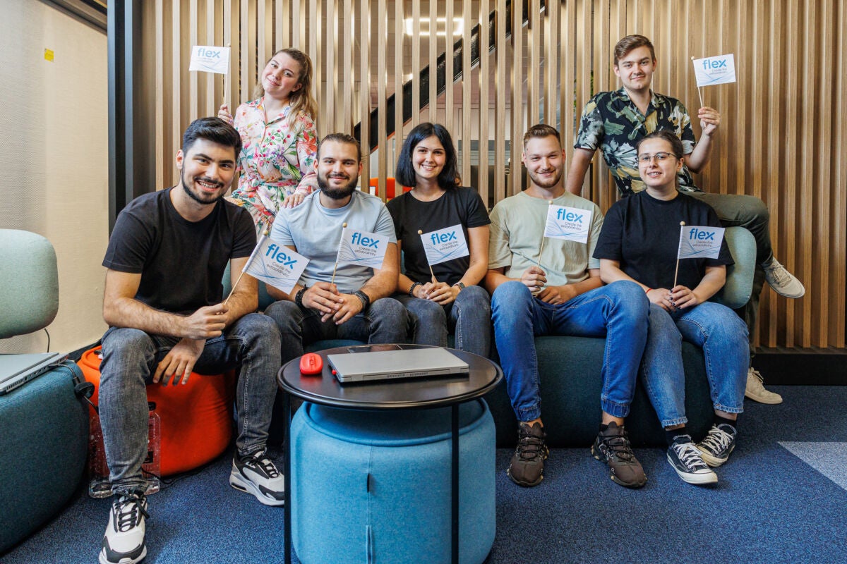 Group picture of Flex interns sitting on a couch holding Flex flags